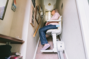 Mujer subiendo una escalera en una silla salvaescalera